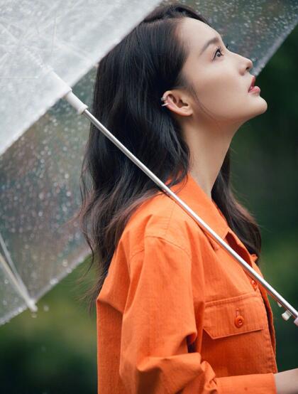 李沁穿橘色外套手持雨伞现身雨天户外慵懒随性写真图片