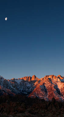 夕阳照射着高山，月亮已经升起的自然风景手机壁纸