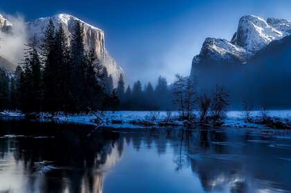 阴天，雪山下寂静的湖泊和寂寥的树木景色图片