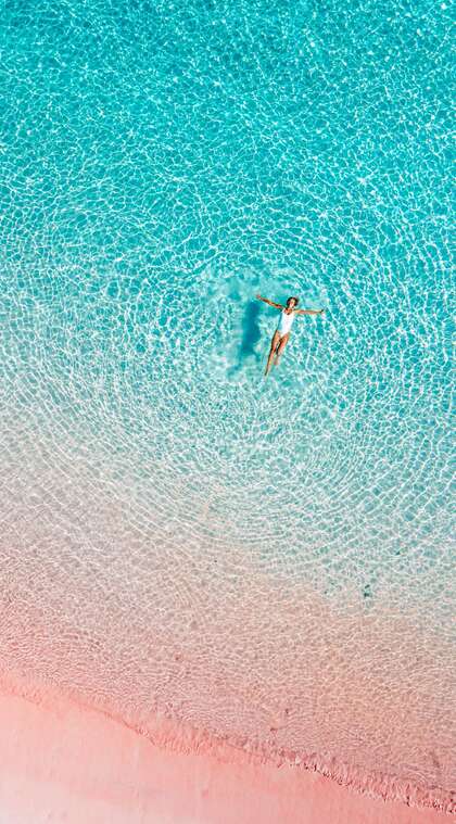 一看就舒心的蔚蓝清澈大海，海岸和海中仰泳的欧美女子唯美高清景色手机壁纸