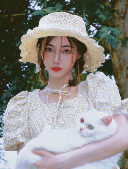 许佳琪头戴草帽，手抱猫咪，身穿小碎花裙户外清新写真图片