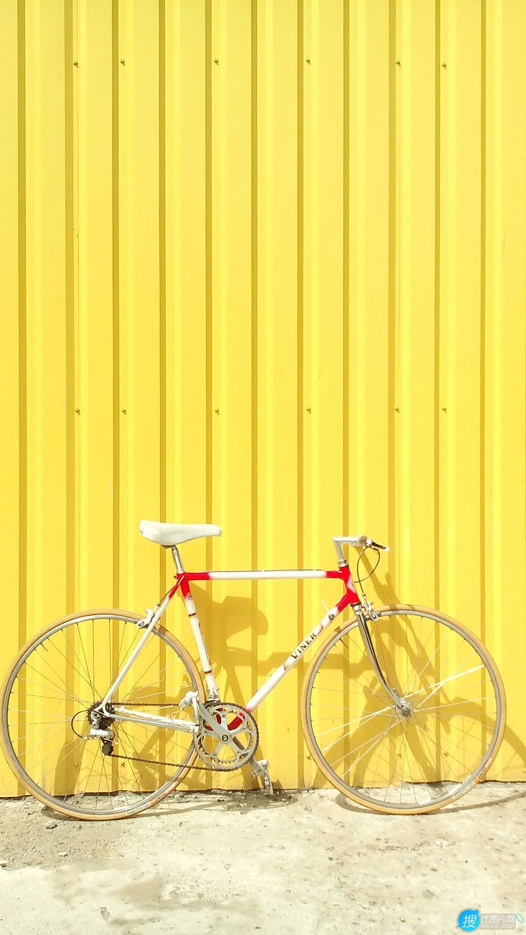 停靠在黄色背景墙前的自行车唯美简约手机壁纸图片