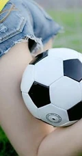 绿茵场上玩足球的 绿衣牛仔短裤妹子写真照片