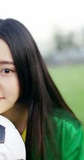 绿茵场上玩足球的 绿衣牛仔短裤妹子写真照片