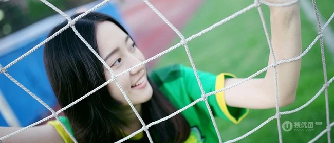 绿茵场上玩足球的 绿衣牛仔短裤妹子写真照片