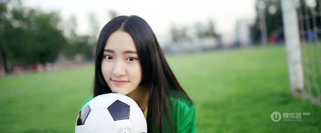 绿茵场上玩足球的 绿衣牛仔短裤妹子写真照片