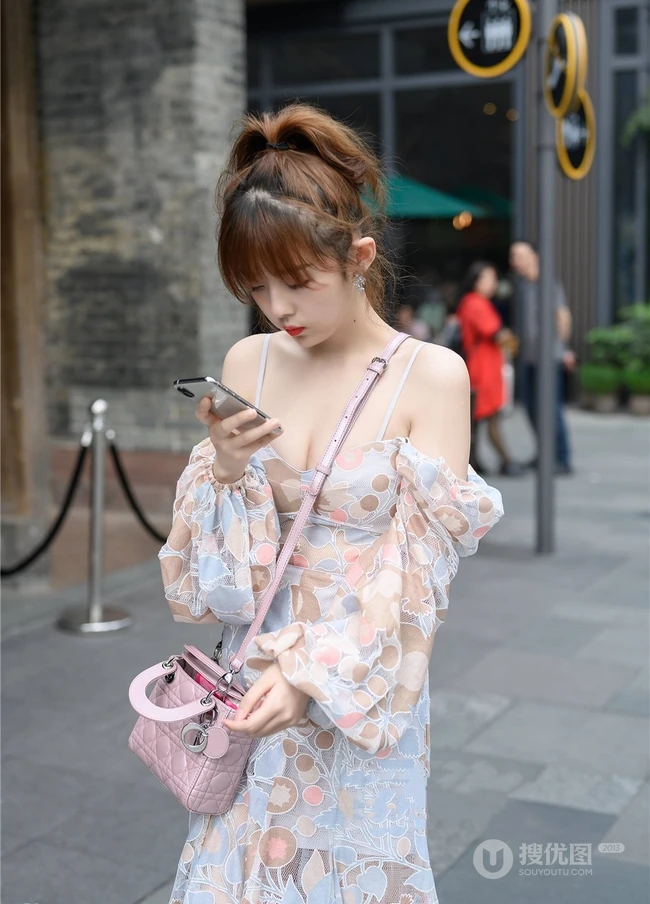 街上玩手机的肩带连衣裙白皙女生气质街拍照片