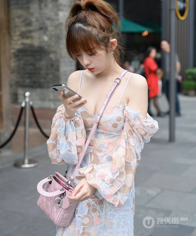 街上玩手机的肩带连衣裙白皙女生气质街拍照片
