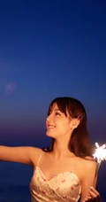 迪丽热巴着肩带裙夜晚海边唯美写真，手拿烟花笑容灿烂