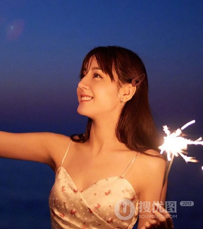迪丽热巴着肩带裙夜晚海边唯美写真，手拿烟花笑容灿烂
