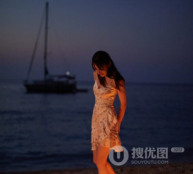 迪丽热巴着肩带裙夜晚海边唯美写真，手拿烟花笑容灿烂