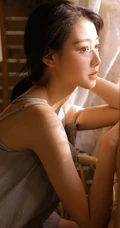 长发大眼线条感小姐姐灰色肩带裙坐藤椅上气质室内写真