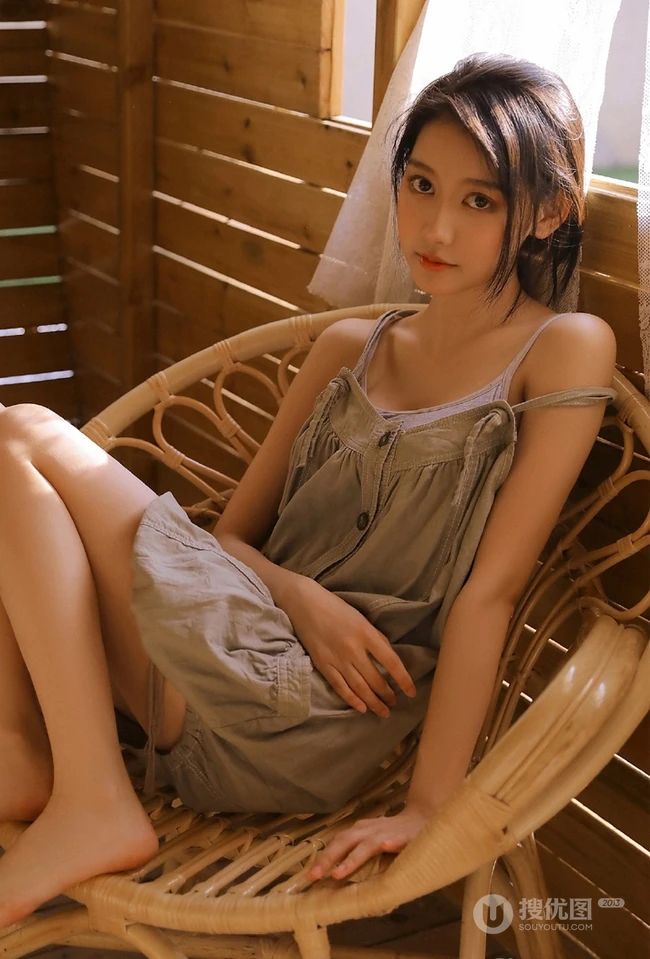 长发大眼线条感小姐姐灰色肩带裙坐藤椅上气质室内写真