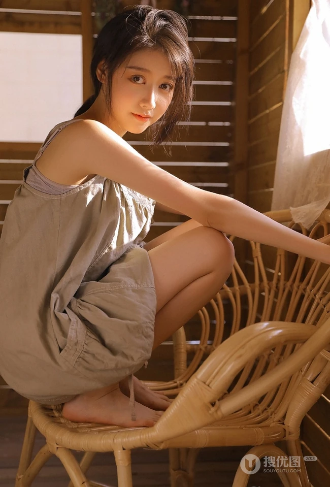长发大眼线条感小姐姐灰色肩带裙坐藤椅上气质室内写真