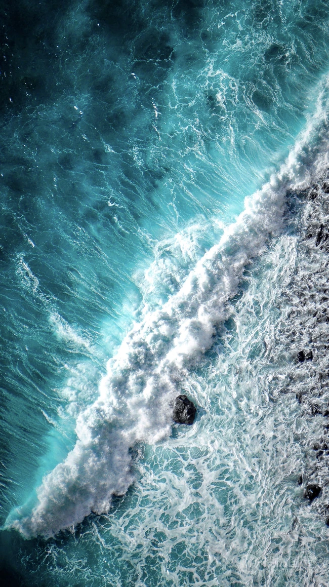 迎着海风踏浪，高清海水拍打沙滩的航拍手机壁纸