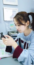 张佳宁休闲针织衫办公室玩手机照片，双马尾造型俏皮可爱