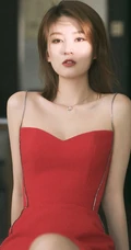 女生乔欣肩带红裙气质出镜，双腿交叉静坐姿态动人