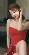 女生乔欣肩带红裙气质出镜，双腿交叉静坐姿态动人