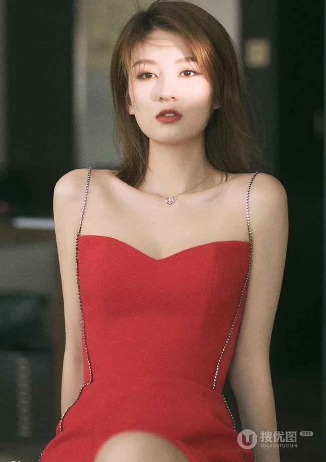 女生乔欣肩带红裙气质出镜，双腿交叉静坐姿态动人