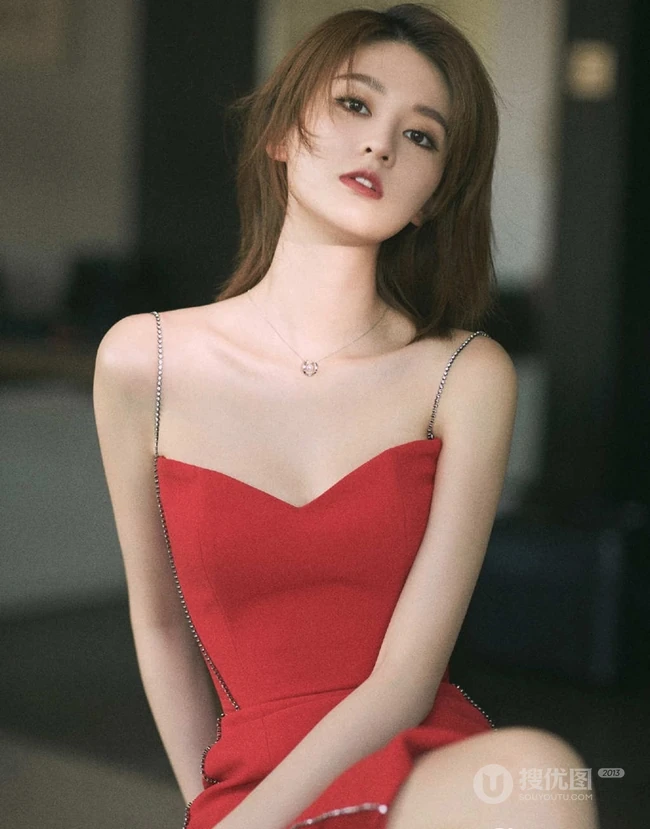 女生乔欣肩带红裙气质出镜，双腿交叉静坐姿态动人