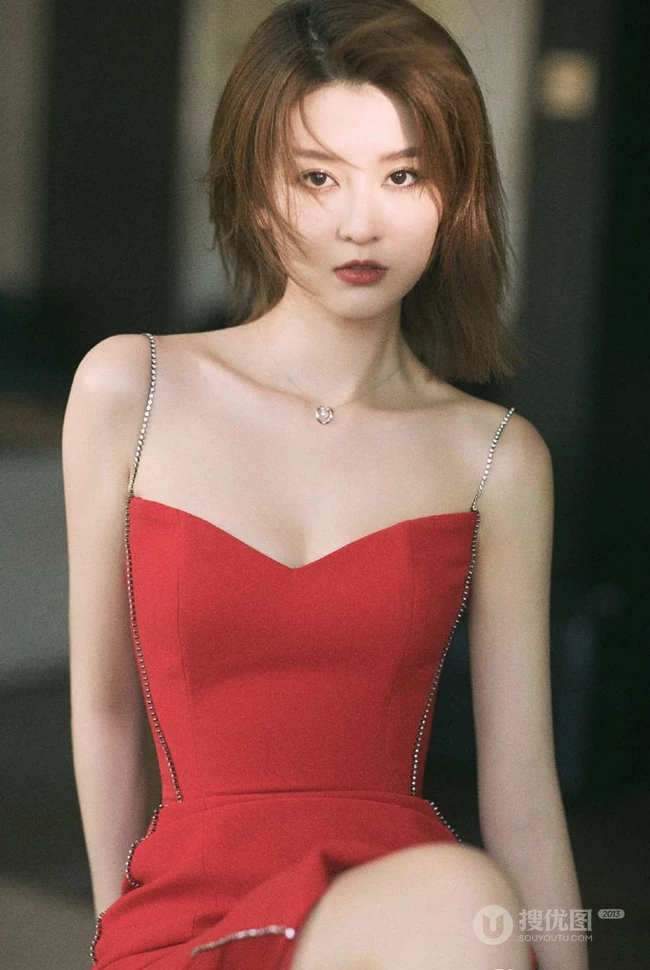 女生乔欣肩带红裙气质出镜，双腿交叉静坐姿态动人
