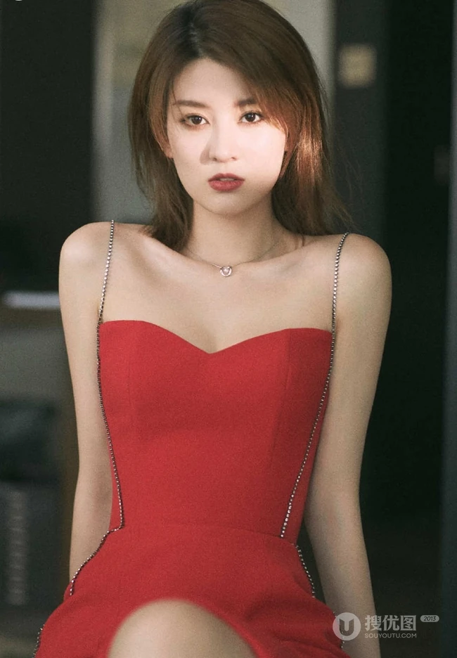 女生乔欣肩带红裙气质出镜，双腿交叉静坐姿态动人