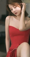 女生乔欣肩带红裙气质出镜，双腿交叉静坐姿态动人