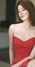 女生乔欣肩带红裙气质出镜，双腿交叉静坐姿态动人