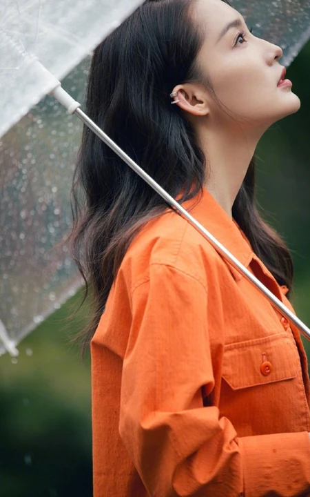 李沁穿橘色外套手持雨伞现身雨天户外慵懒随性写真图片