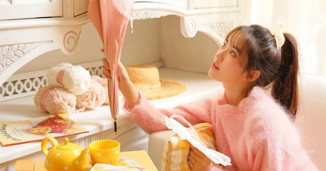 高扎马尾的浅粉少女，着粉色羊毛衣搭短裙室内享受阳光写真