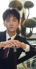 牛骏峰手拿小拐杖，身穿黑色西装沉稳帅气写真图片