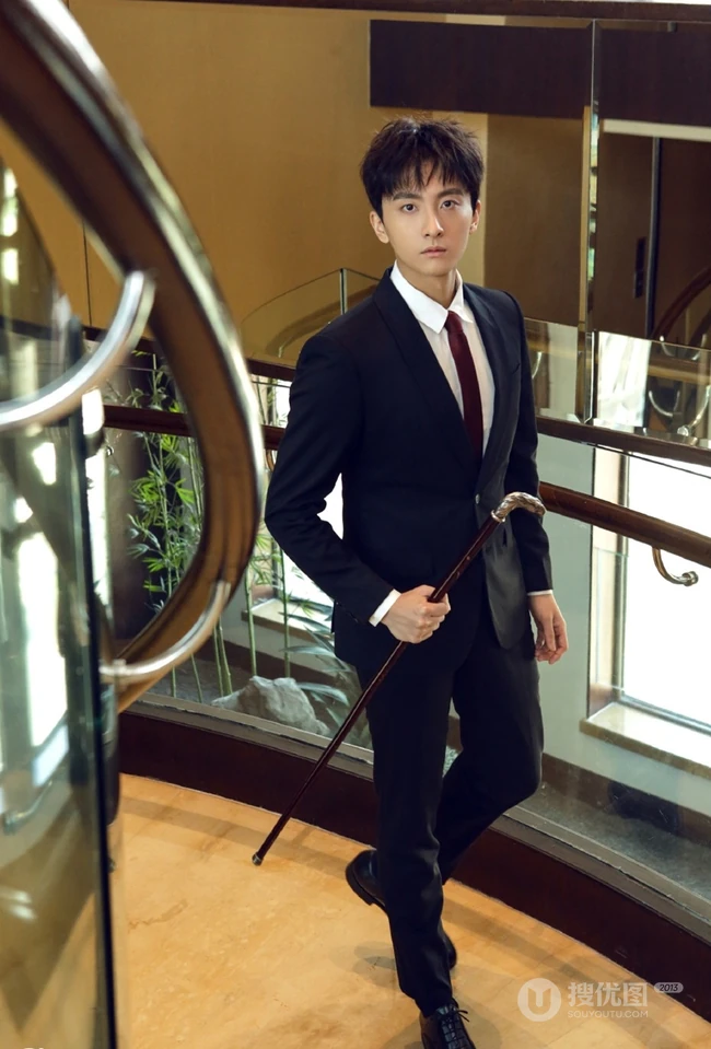 牛骏峰手拿小拐杖，身穿黑色西装沉稳帅气写真图片