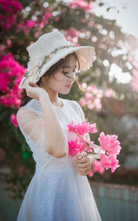 手拿鲜花带帽子的清纯美女高清手机壁纸