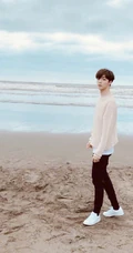 陈立农休闲毛衣黑裤现身海边沙滩，张开双臂拥抱大海，画面清新