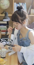戴黑框眼镜的大眼萌圆脸少女室内玩显微镜可爱写真图片