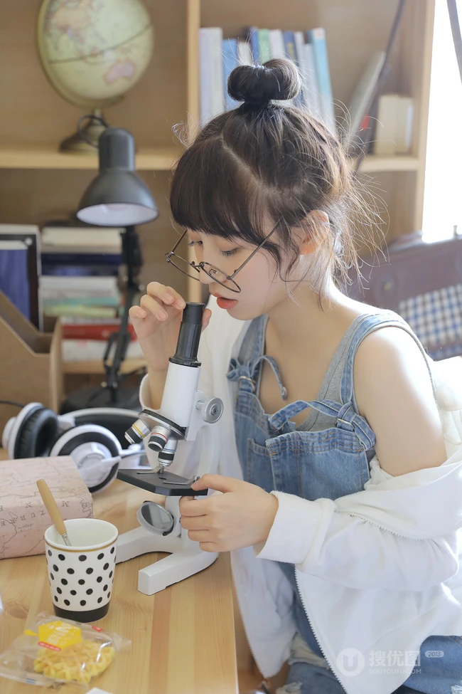 戴黑框眼镜的大眼萌圆脸少女室内玩显微镜可爱写真图片