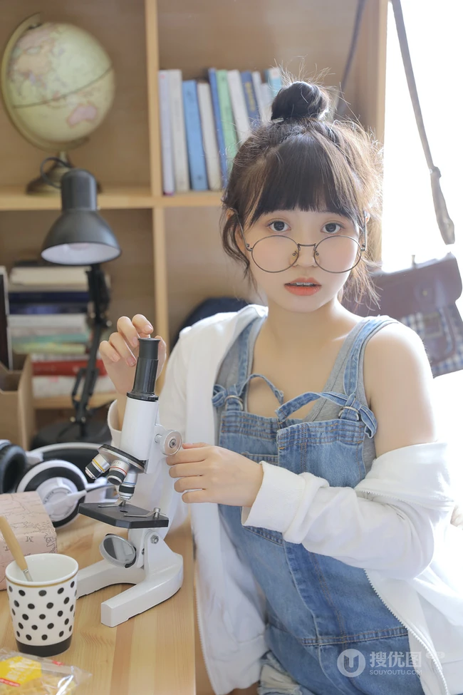 戴黑框眼镜的大眼萌圆脸少女室内玩显微镜可爱写真图片