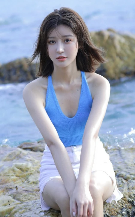 海边礁石上戏水的清凉蓝色背心短裤女生气质唯美写真图片