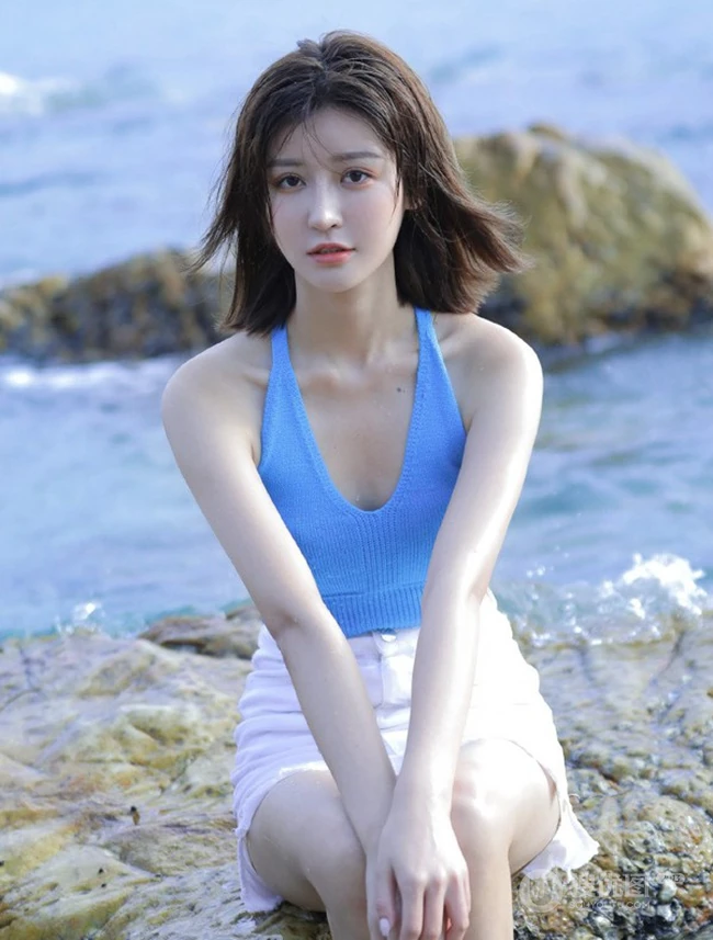 海边礁石上戏水的清凉蓝色背心短裤女生气质唯美写真图片