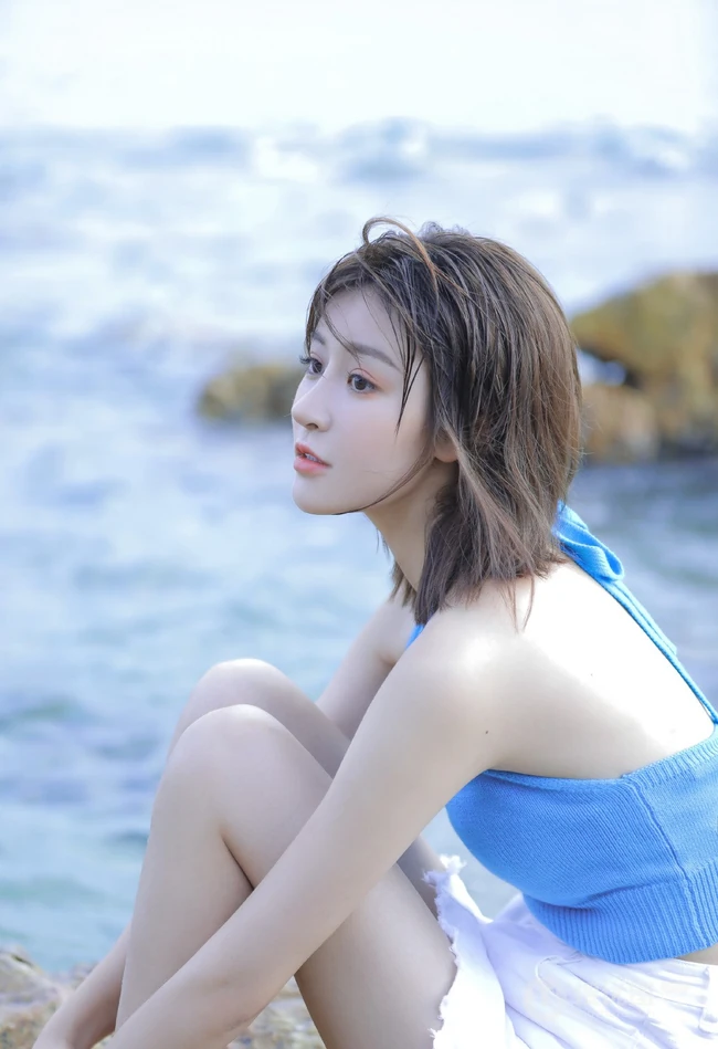 海边礁石上戏水的清凉蓝色背心短裤女生气质唯美写真图片