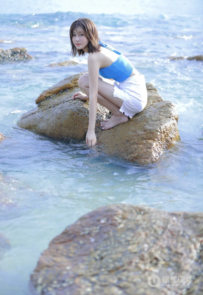 海边礁石上戏水的清凉蓝色背心短裤女生气质唯美写真图片