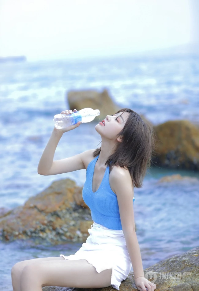 海边礁石上戏水的清凉蓝色背心短裤女生气质唯美写真图片