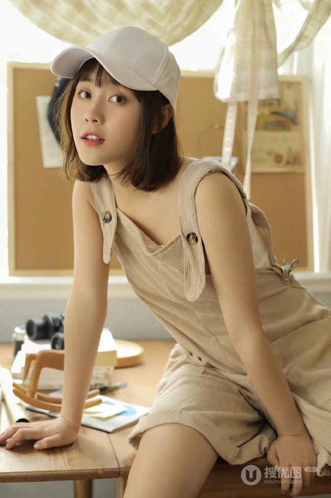 戴棒球帽的短发女生小姐姐穿着好看的背带裤居家悠闲写真图片