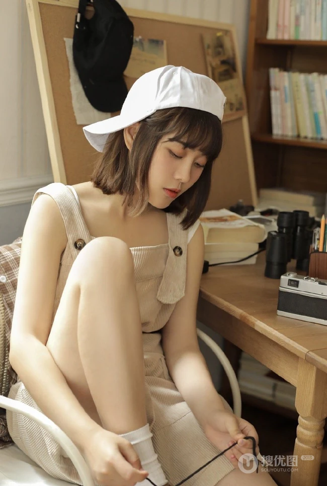 戴棒球帽的短发女生小姐姐穿着好看的背带裤居家悠闲写真图片