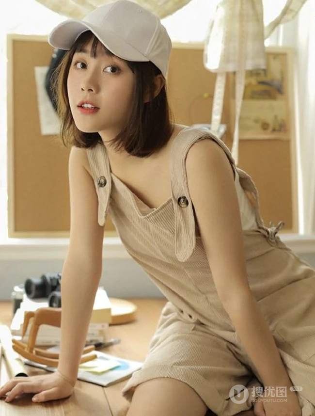 戴棒球帽的短发女生小姐姐穿着好看的背带裤居家悠闲写真图片