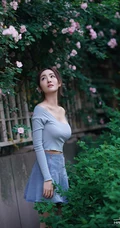 气质美丽女孩蔷薇花前驻足流连，着V领上衣搭牛仔裙艺术摄影图片
