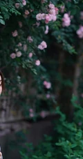 气质美丽女孩蔷薇花前驻足流连，着V领上衣搭牛仔裙艺术摄影图片