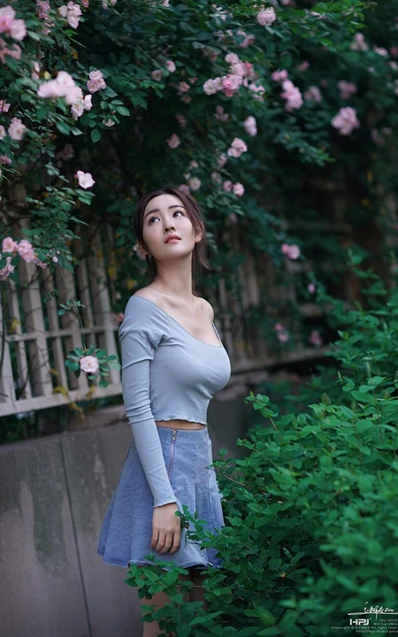 气质美丽女孩蔷薇花前驻足流连，着V领上衣搭牛仔裙艺术摄影图片