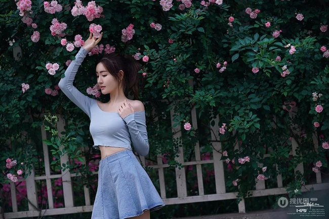 气质美丽女孩蔷薇花前驻足流连，着V领上衣搭牛仔裙艺术摄影图片