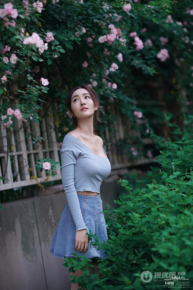 气质美丽女孩蔷薇花前驻足流连，着V领上衣搭牛仔裙艺术摄影图片